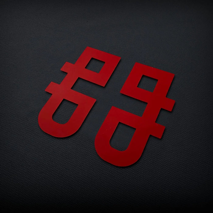 Raised silicone logo badge in red, with smooth edges and clean solid shapes